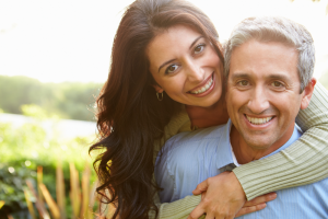 mature couple embracing in a field and smiling